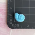 Detailed close-up of a mini blue resin conch shell charm, perfect for DIY phone case craft. - Spiral Conch