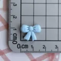Mini light blue resin bow charm detail view showing actual product size on measurement grid. - Blue Mini Bowknot
