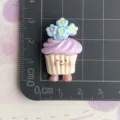 Resin cupcake flatback charm detail showing cute face design and blue flower decoration on mat. - Purple Cake with Blue Flower (B012) / Set of 3 / Purple