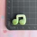 Close-up of green resin music note charm with colorful star patterns for DIY decor. - Green