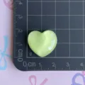 Close-up detail of light green glitter heart resin charm for DIY craft and accessories. - Green Glitter Heart