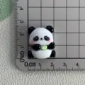 Close-up detail of cute resin panda charm with flower bowl on measurement grid, ideal DIY accessory. - Panda with Bib