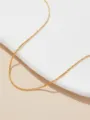 Macrodetail van de textuur van een minimalistische gouden titaniumstalen halsketting zonder hanger - Goud