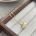 Primer plano detallado de un collar con colgante de doble corazón brillante en bandeja. - Dorado