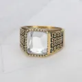 Close-up of a men's square clear gemstone ring with gold-tone Greek key detailing. - Size 7 / White
