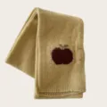 Knit winter scarf detail showing the cute red apple pattern and soft woolen texture clearly. - Beige