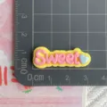 Dettaglio del ciondolo con lettera Sweet in resina fai da te per decorare la cover - SWEET / Finitura lucida / Giallo