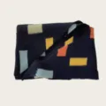 Close-up detail of a stylish navy knit scarf featuring colorful geometric block patterns. - 140cm / Navy Blue