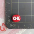 Primo piano di un piccolo ciondolo con lettera OK in resina rossa per forcine fai da te e bricolage. - Segno OK Rosso / Confezione Mini