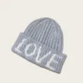 Détail de bonnet en tricot gris montrant la broderie de lettres LOVE blanches texture gros plan - Taille unique / Gris clair
