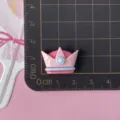 Detailed close-up of a pink and blue crown resin flatback charm for DIY crafts and accessories. - Pink