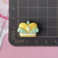 Detailed close-up of glossy yellow green crown resin cabochon charm for DIY crafts. - Yellow