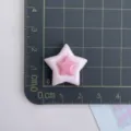 Detaillierte Nahaufnahme eines niedlichen rosa Harz Stern-Anhängers auf einer Messmatte. - Rosa Rand Stern