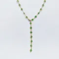 Primo piano dettagliato della collana a Y dorata con pietre di vetro verde incastonate. - Verde chiaro