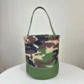 Vue détaillée d'un sac seau en toile camouflage avec une base verte et une longue anse - Camouflage