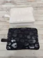 Detail showing black and white leopard print cosmetic bags with a glossy finish texture - White