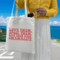 Detailed view of cream canvas tote bag featuring red #MAMALIFE printed slogan design - Style 6