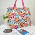Large canvas tote bag featuring a colorful all-over smiley face print with pink handles. - Cartoon Face