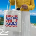 Canvas tote bag with '4th of July' print held by model in outdoor scenic setting - Style 9