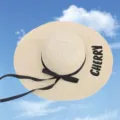 Straw sun hat detail with elegant black bow and CHERRY embroidery on the wide brim - One Size / Beige