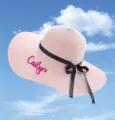 Customized pink straw sun hat with black ribbon bow and 'Cailyn' embroidery detail view - One Size / Pink