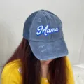 Close-up detail of distressed denim Mama embroidery baseball cap with mesh back on model - Navy Blue