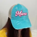 Detail view of a blue distressed denim trucker hat with Mama print worn by a model. - Mint Green