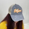 Detail view of washed gray distressed trucker hat with orange Mama print worn by model - Gray