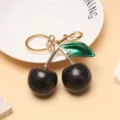 Gros plan détaillé d'un porte-clés cerise noire avec finition pailletée et doré - Noir Vert Or