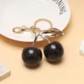 Vue détaillée d'un porte-clés cerise noire avec feuille d'or et finition scintillante - Noir Foncé Paillettes