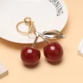 Vue détaillée du porte-clés cerise rouge scintillant avec finitions dorées - Paillettes rouges