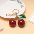 Détail du pendentif cerise rouge pailletée avec anneau de porte-clés en métal doré poli - Rouge Vert Or