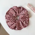 Détail en gros plan d'un chouchou rose motif léopard cœur avec bord volanté, attache cheveux. - Chouchou Léopard Rouge Simple Couche