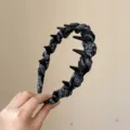 Detailopname van geplooide stoffen haarband met tanden en zwarte paisley print voor haar. - Haarband met zwarte print