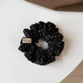 Detailed view of the black fabric scrunchie with white patterns and handmade tag. - Small Scrunchie / Black Leopard Polka Dot
