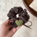 Detail view of the floral scrunchie with green heart charm and bow for daily hairstyles. - Brown Floral Green Heart