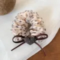 Gros plan détaillé d'un chouchou à pois en organza doux avec nœud marron et breloque cœur. - Chouchou Beige à Pois Cœur