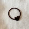 Detailed shot of a dark brown hair tie with a glossy polka dot heart ornament for daily use. - Coffee Polka Dot Hair Tie / Hair Tie