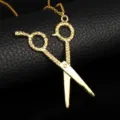 Detailed macro view of gold-colored scissors pendant with intricate textured handles on chain - Gold