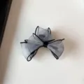 Gros plan sur la pince à cheveux noeud en organza translucide avec bordure noire et subtils reflets. - 7cm / Pince à Cheveux Nœud Ruban Bleu et Blanc