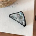 Primo piano dettagliato della pinza per capelli triangolare elegante con acetato perlato. - Iridescenza di conchiglia
