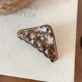 Primo piano di un elegante mollettone per capelli in acetato tartarugato su sfondo di libro. - marrone ambra