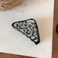 Dettaglio del fermaglio per capelli triangolare geometrico bianco e nero, accessorio in acetato. - Motivo a macchie