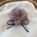 Vista dettagliata di un elastico per capelli in rete con fiocco marrone e cuore a quadri. - Pois Rosa