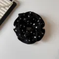 Detail view of a black hair scrunchie with white polka dots, showing soft pleated fabric. - Black 4 Layer Scrunchie