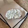 Nahaufnahme einer schicken Stoff-Haarbananenklammer mit Polka-Dots und zarten Perlen. - Cremefarbener Bananen-Clip mit Punkten