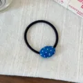 Detail shot of a blue oval polka dot hair tie on linen fabric, sweet daily hair accessory. - Blue