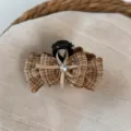 Close-up detail of the brown plaid bow hair claw, showing the tweed texture and crystal. - Light Coffee