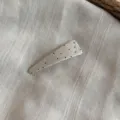 Primer plano de la pinza de pelo de tela plisada con lunares, mostrando textura y detalles. - Blanco Crema-Horquilla Clic Clac Triangular
