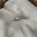 Detailaufnahme einer minimalistischen silbernen Wellen-Haarspange auf strukturiertem Stoff. - Welle (Helles Silber)